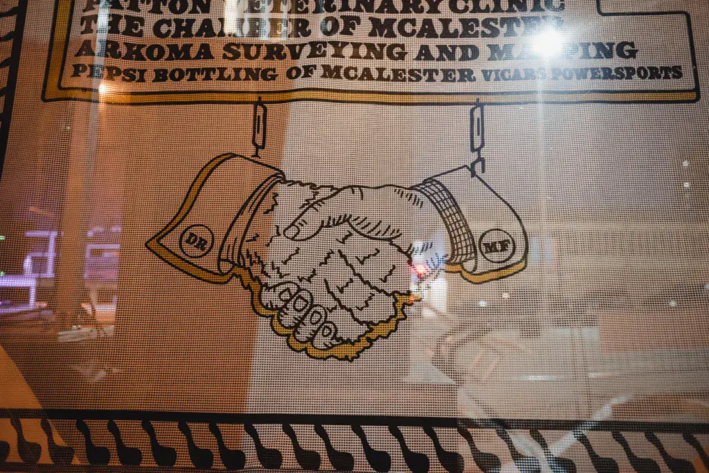 Sponsor signage at Dancing Rabbit Music Festival displays a handshake illustration and business names on a screen.
