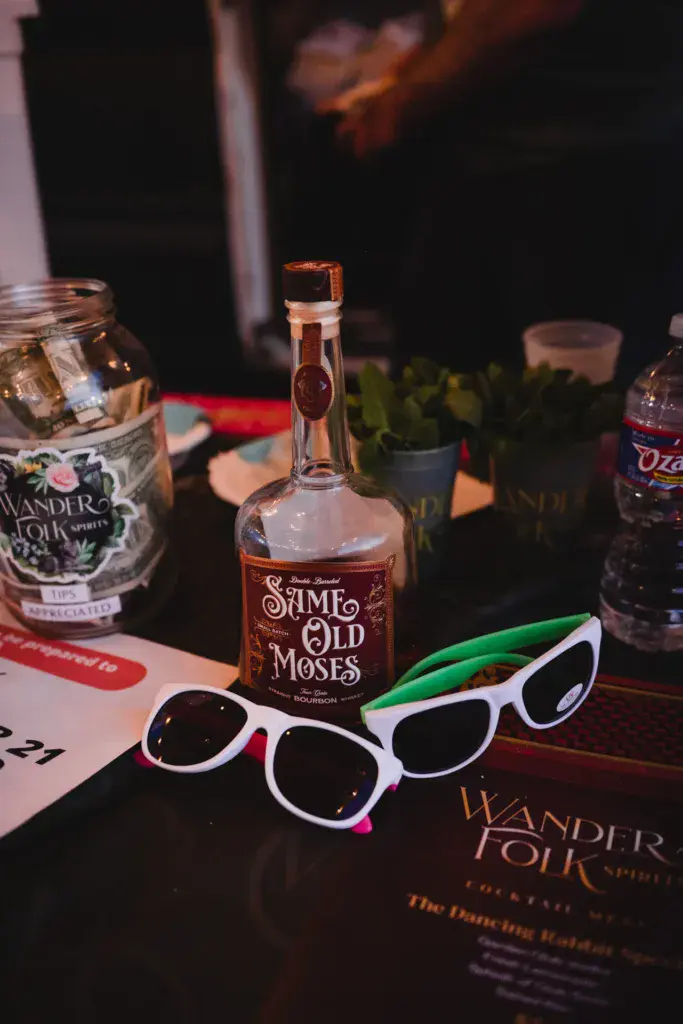 Sponsor bottles and novelty sunglasses displayed on a table at an evening festival event.