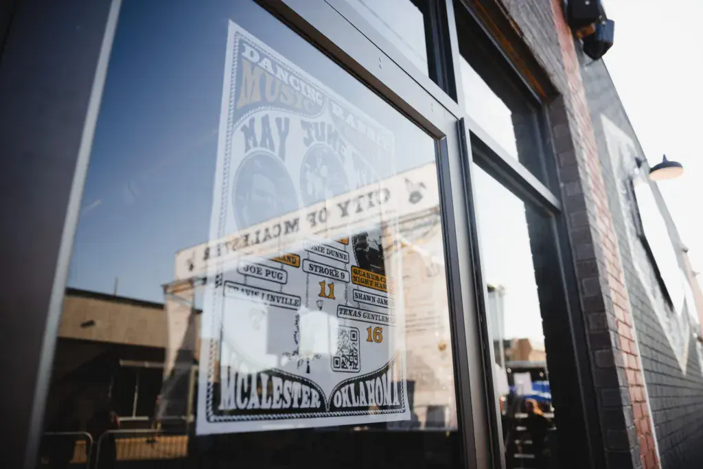 Festival promotional poster and signage displayed in a window with venue buildings visible in the background.