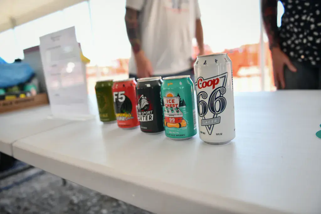 A close-up display of various colorful beverage cans arranged on a white table at the festival.