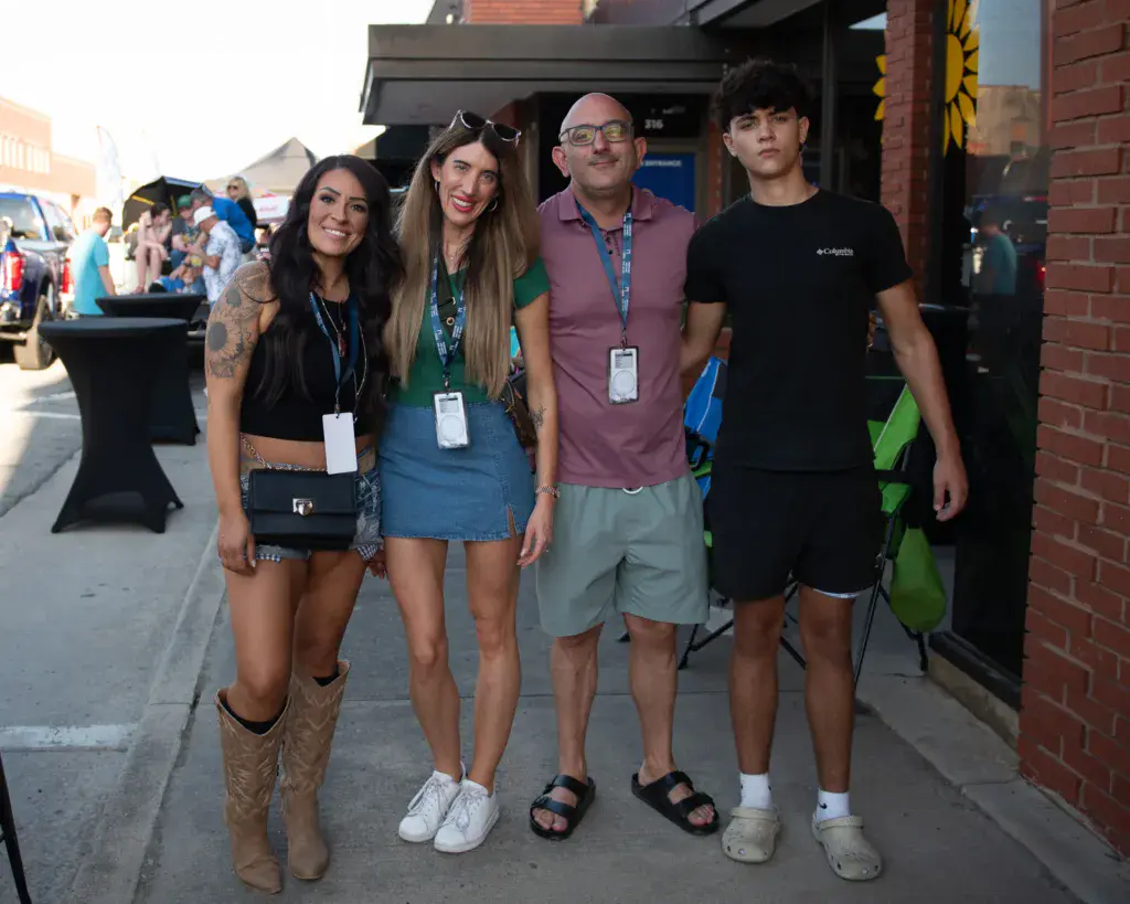 Four people wearing festival credentials stand together on a brick building exterior during the Dancing Rabbit Music Festival.