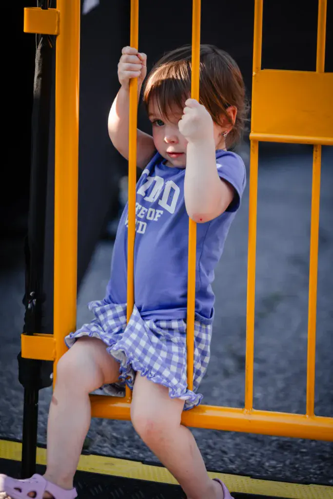 A young child sitting on a bright yellow playground structure, looking toward the camera.