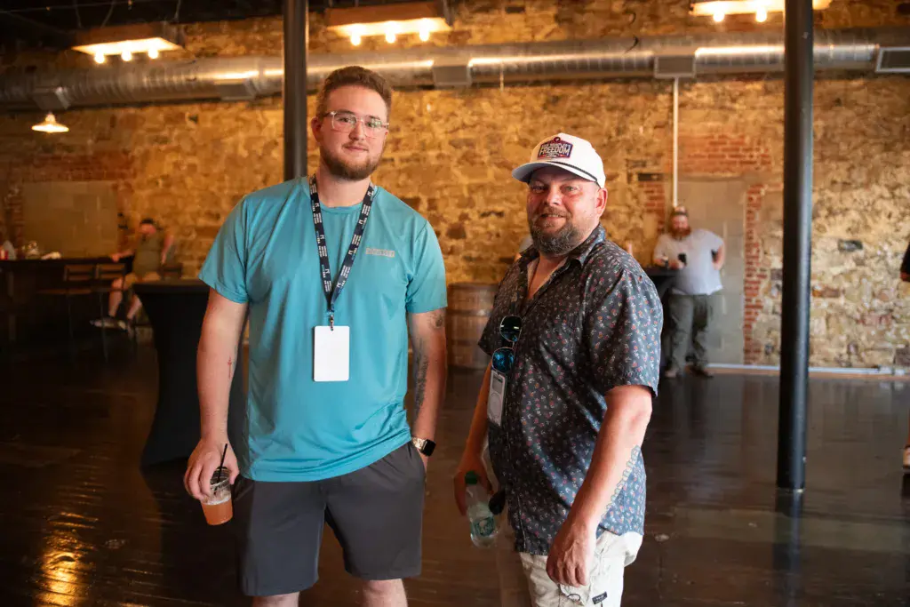 Two people wearing credential badges stand together inside an industrial brick venue at the festival.