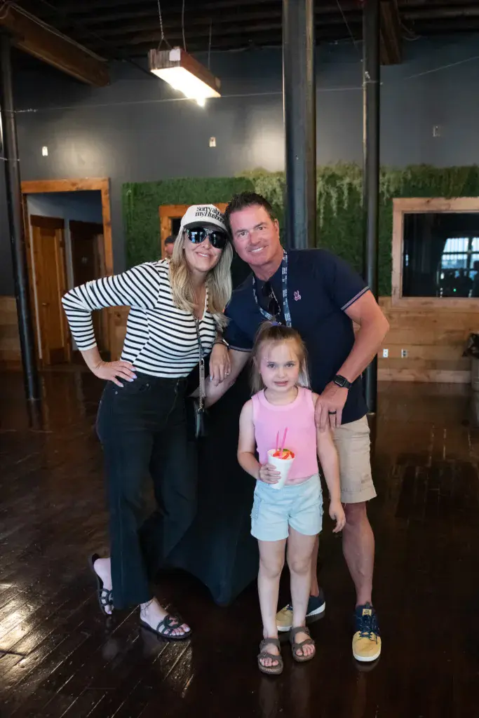 Three people posing together indoors at Dancing Rabbit Music Festival venue.
