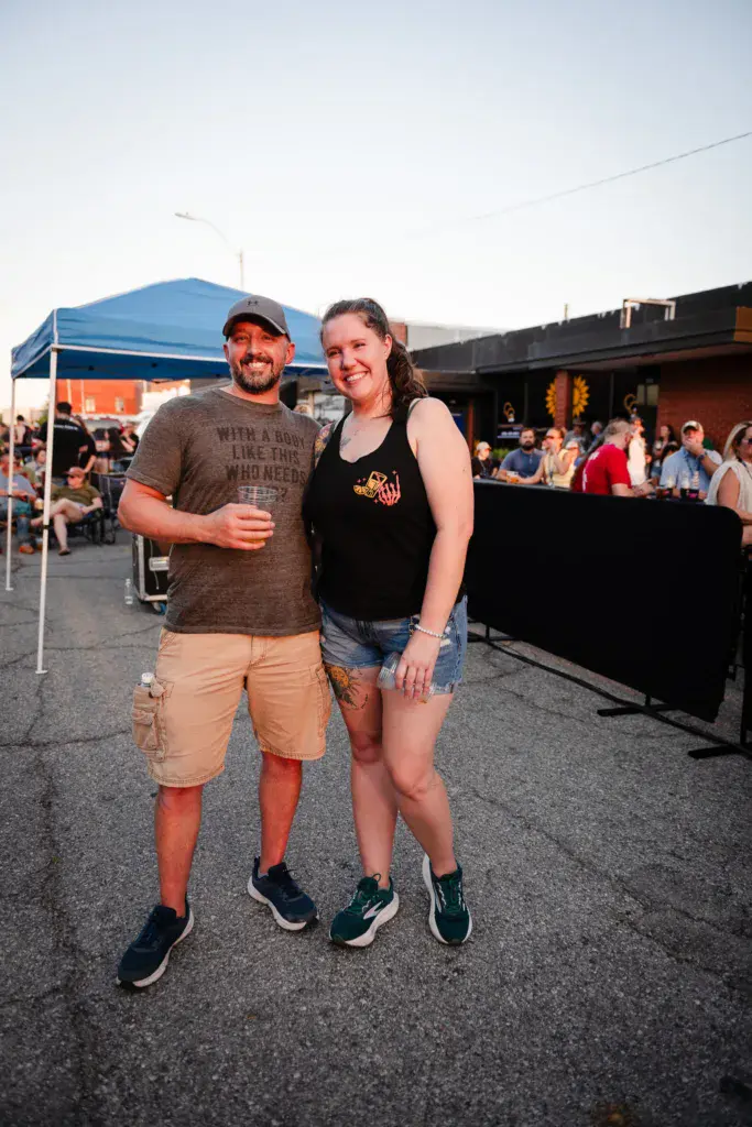 Two smiling attendees pose together at the Dancing Rabbit Music Festival outdoor venue.