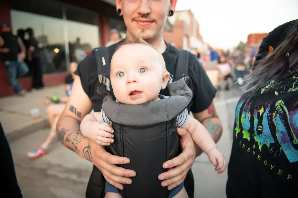 A festivalgoer holds an infant while standing among the crowd at Dancing Rabbit Music Festival.
