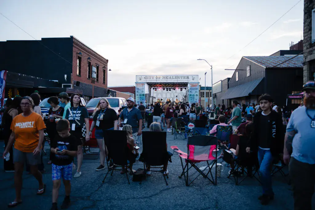 Crowd of festival attendees gathered in an outdoor urban venue with a stage and signage visible in the background.