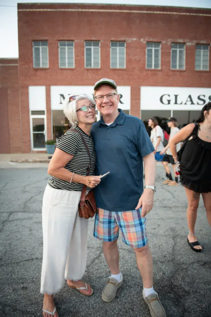 Two attendees posing together in front of a brick building at the Dancing Rabbit Music Festival.