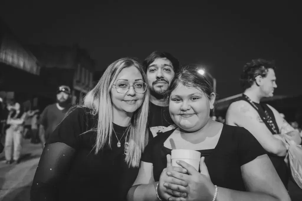 Three attendees smile at the camera while standing in a crowd at the Dancing Rabbit Music Festival.