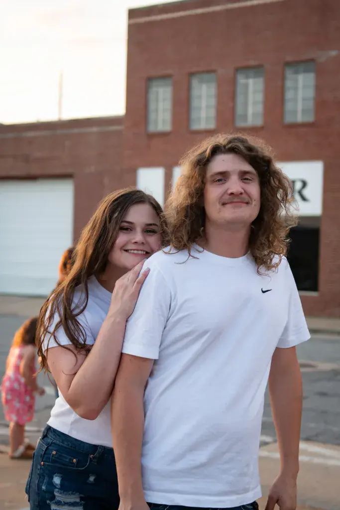 Two smiling young people pose together in front of a brick building at the festival venue.