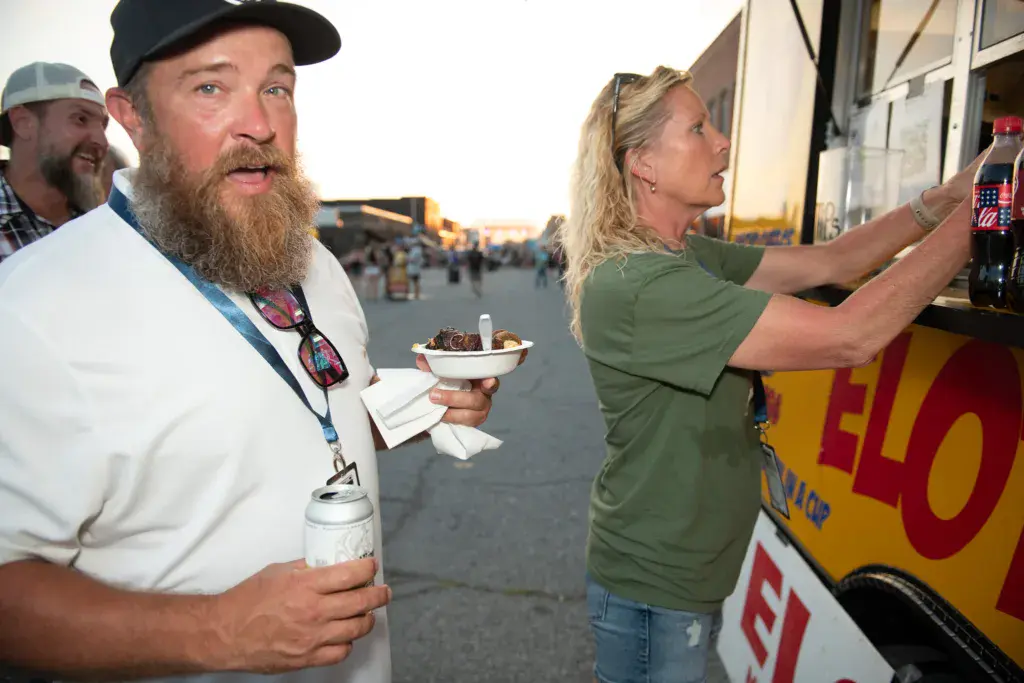 Festival attendees enjoy food and drinks at a vendor stand during the Dancing Rabbit Music Festival.