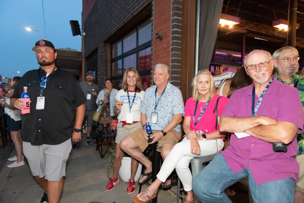 Festival attendees wearing credential badges gather together at an outdoor venue during evening hours.