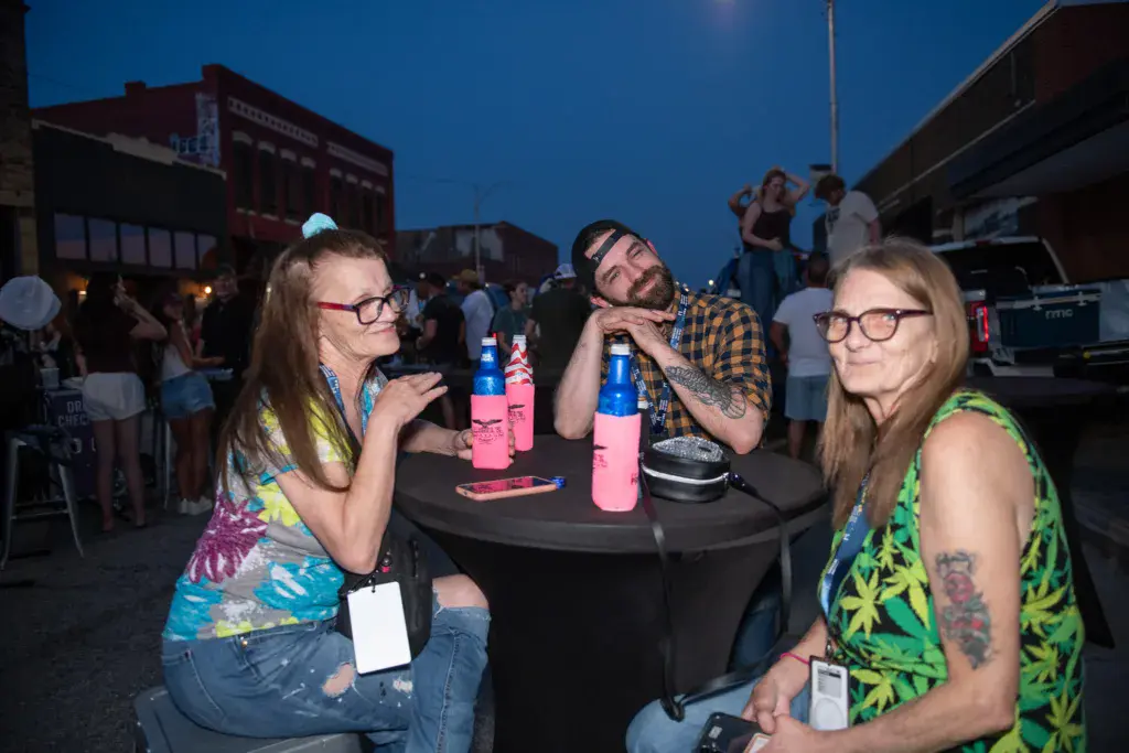 Festival attendees gather at a table with drinks during an evening event at Dancing Rabbit Music Festival.