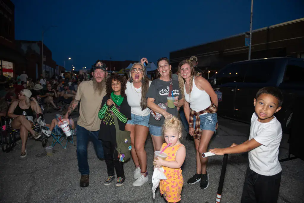 A group of festivalgoers of varying ages smile and pose together during an evening at Dancing Rabbit Music Festival.