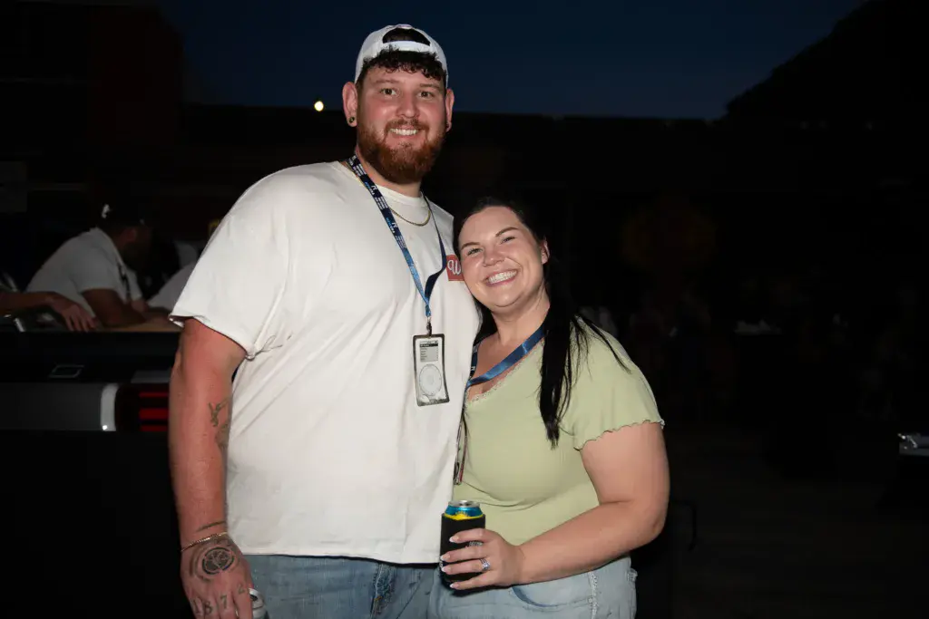 Two festival attendees wearing credential lanyards smile together at night during the event.