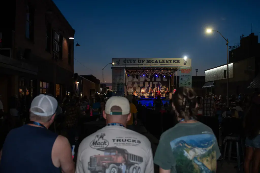 Evening crowd watches performers on an illuminated stage at the Dancing Rabbit Music Festival in McAlester.