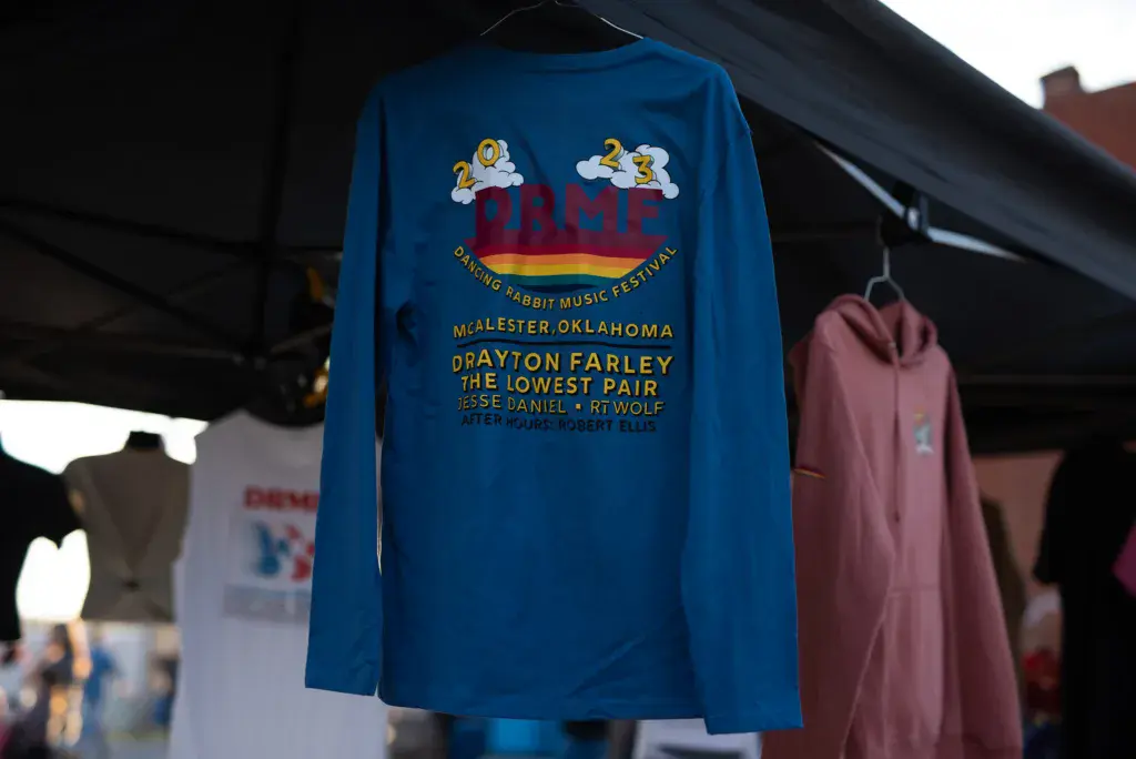 A blue long-sleeve festival t-shirt hanging on display at the Dancing Rabbit Music Festival.