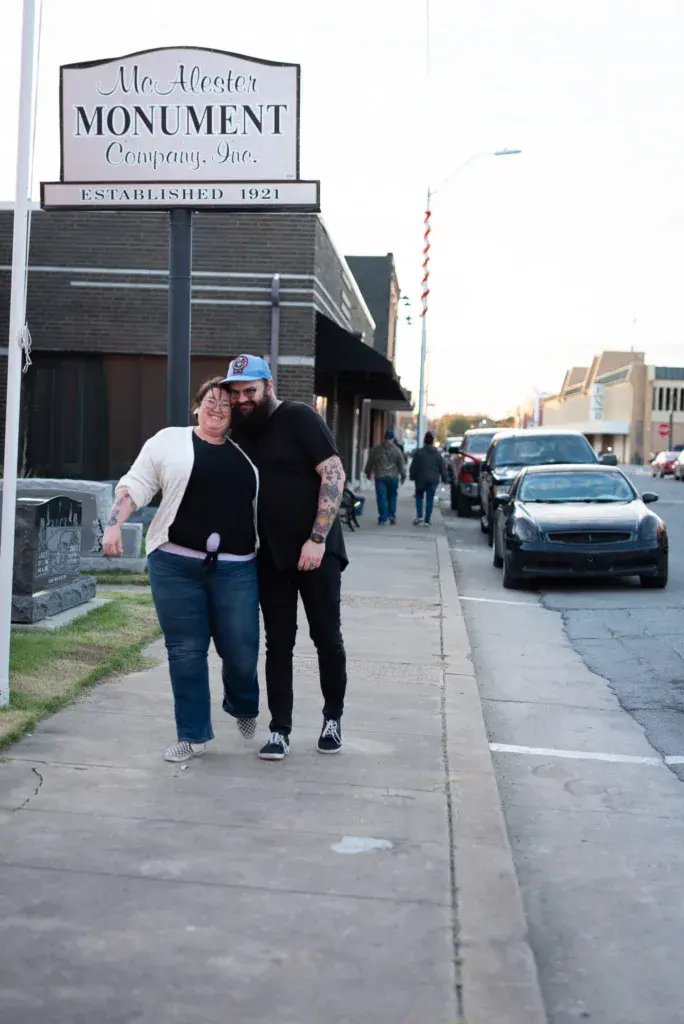 Two people walking together on a sidewalk in front of a historic monument company building.