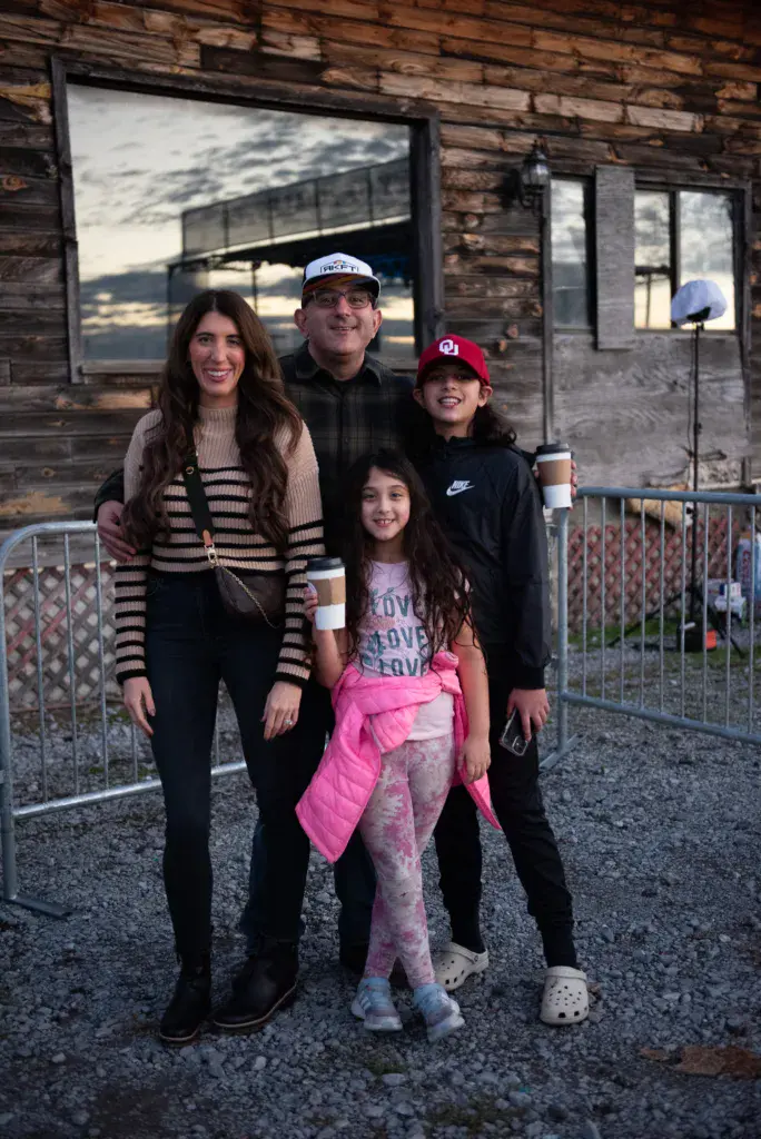 A family of four poses together in front of a rustic brick building at the festival.