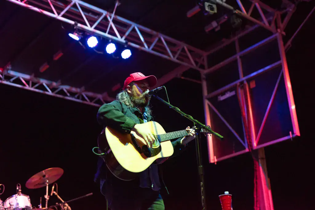Guitarist performing on stage under colorful lighting at Dancing Rabbit Music Festival.