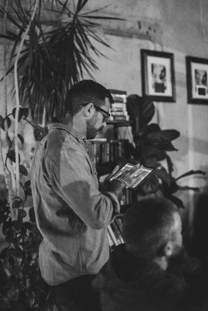 A person wearing glasses looks at merchandise inside an indoor venue decorated with plants and framed artwork.