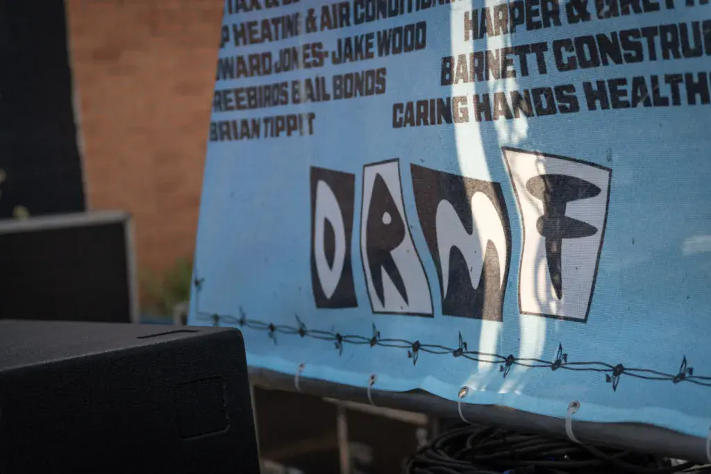 A blue banner displaying sponsor names and the word 'DONATE' in large letters at an outdoor event.