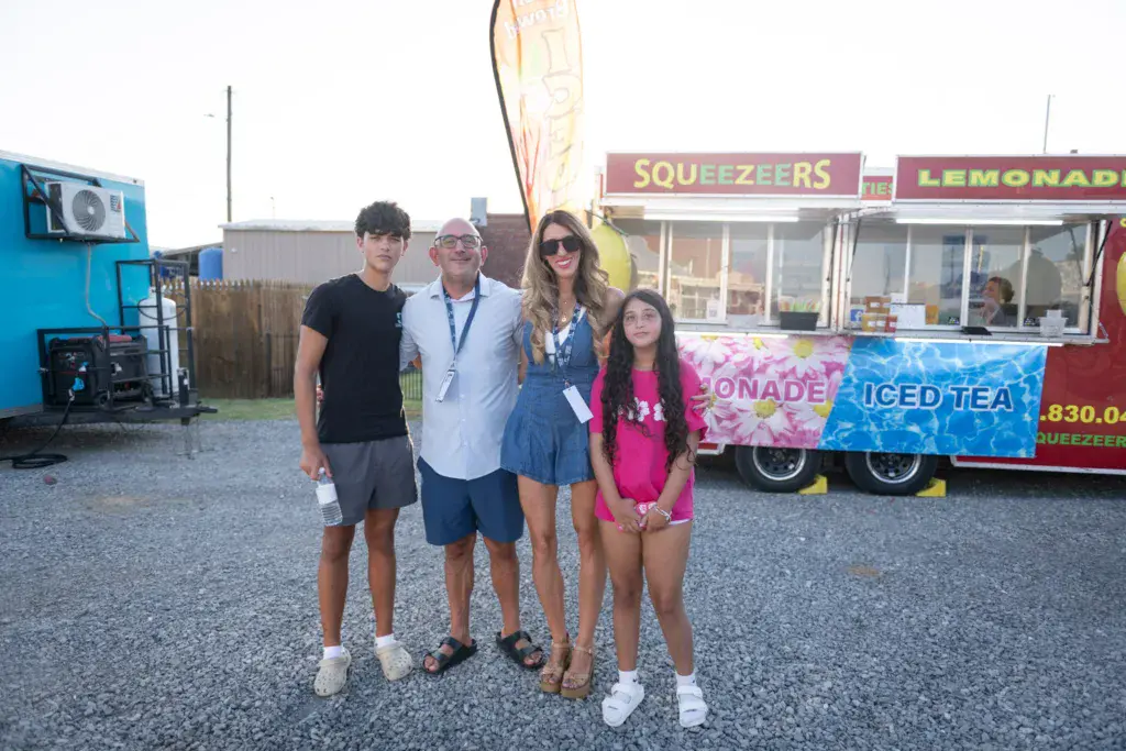 Four people pose together at the Dancing Rabbit Music Festival near food vendor trucks.