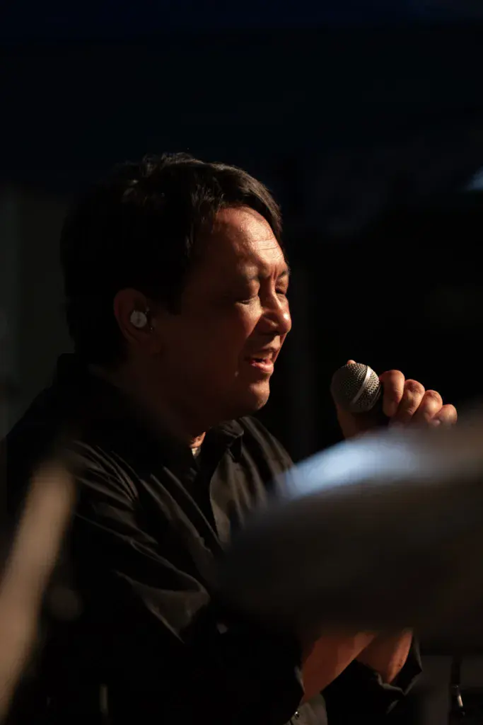 A performer singing passionately into a microphone on stage during an evening performance.