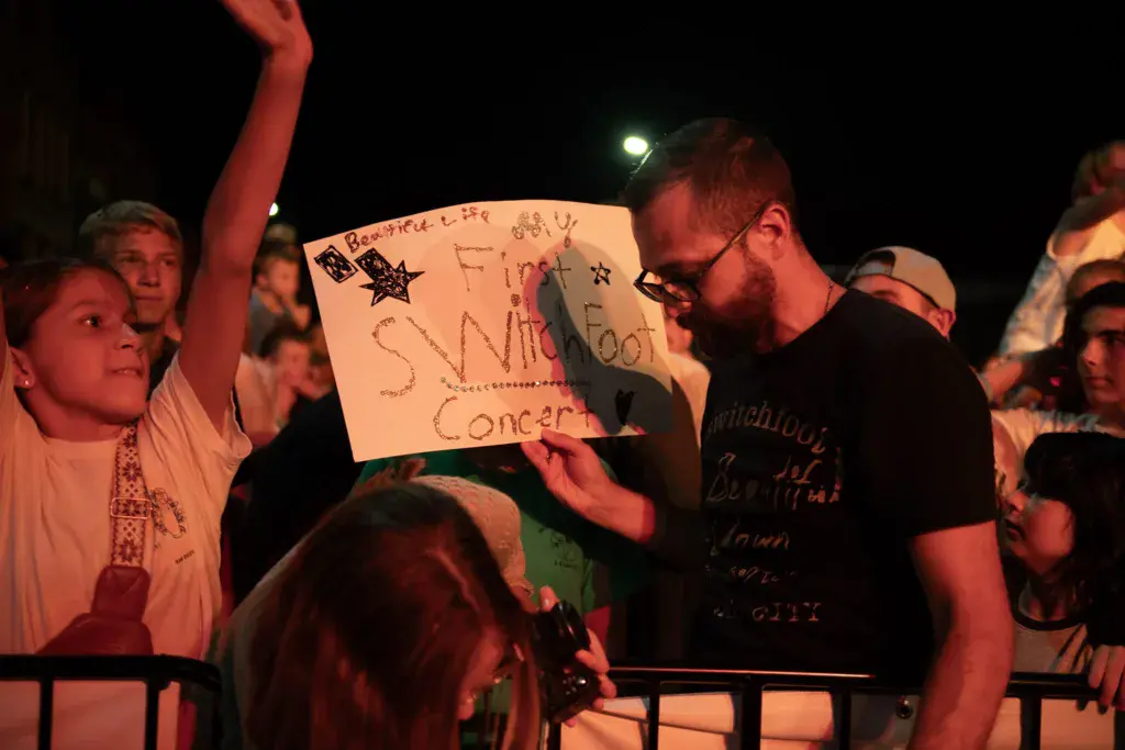 Nighttime crowd at Dancing Rabbit Music Festival holds up a handmade sign during a performance.