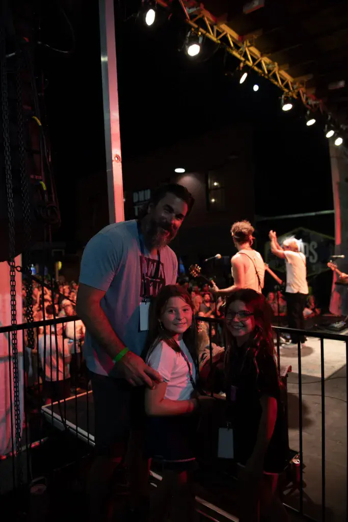 Festival attendees enjoy the show from a designated area near the stage with performers visible in the background.