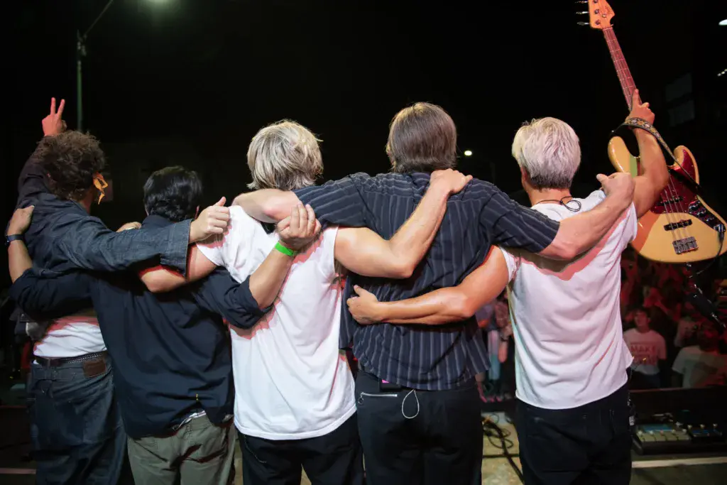 Band members and performers link arms together on stage during an evening performance at the festival.